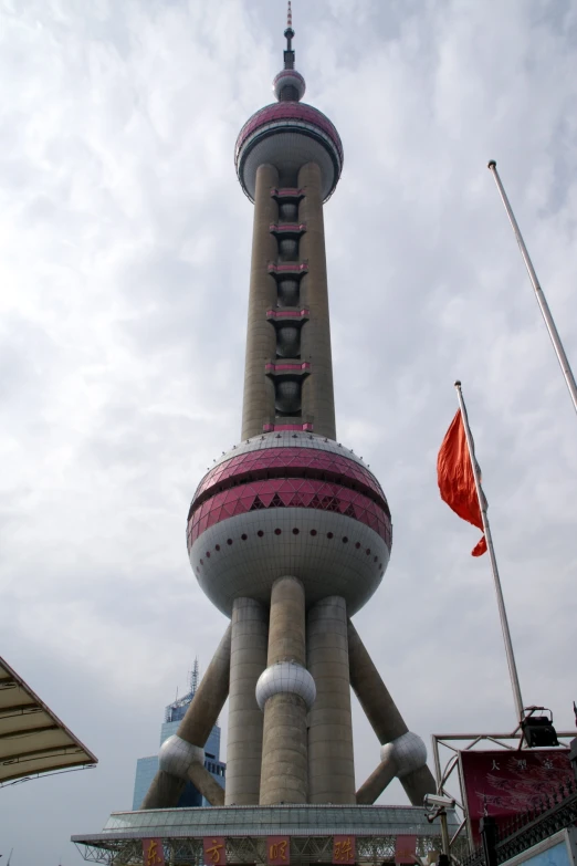 an unusual structure with a very tall spire stands above flags