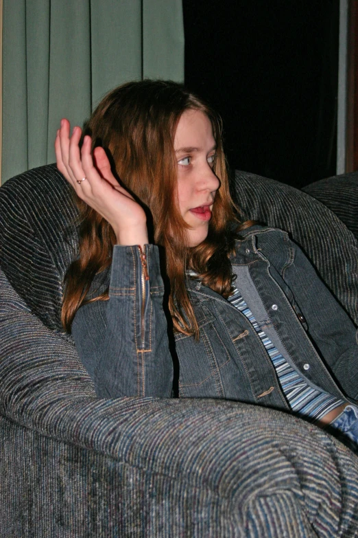 a girl in jean jacket sitting on a couch