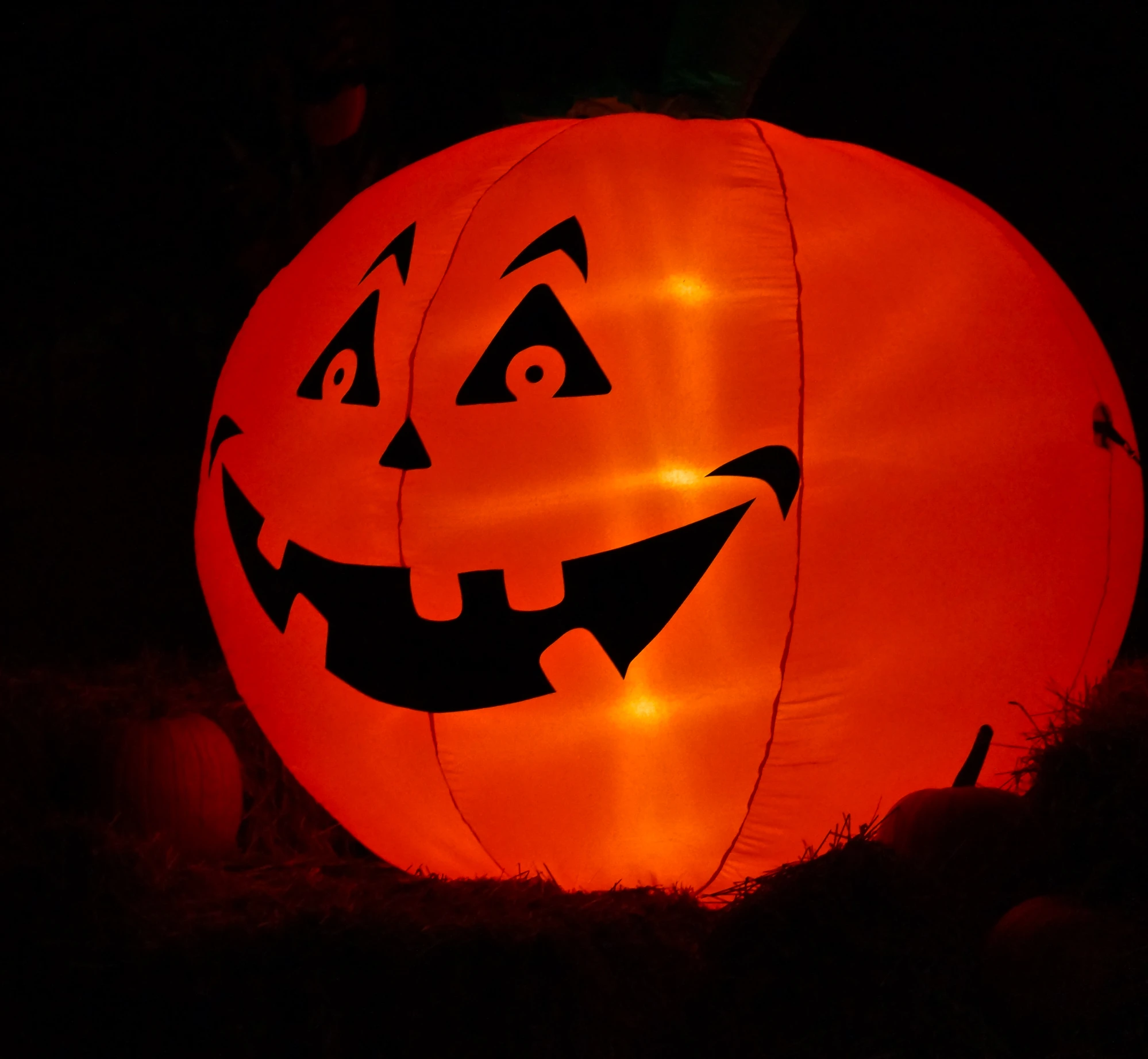 a lit up pumpkin lantern sitting on top of a grass covered field