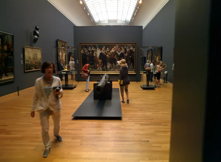 people are walking through the museum with paintings