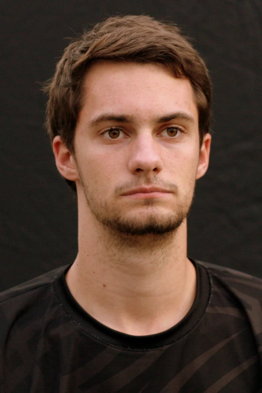 a young man standing in front of a black background