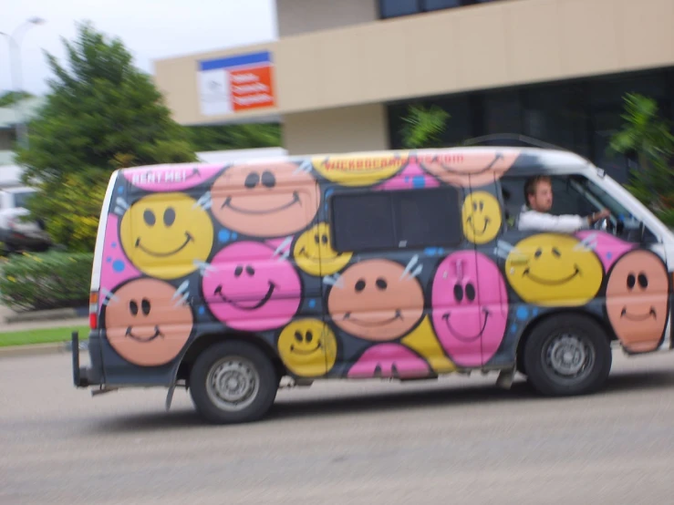 a woman driving a vehicle with smiley faces painted on it