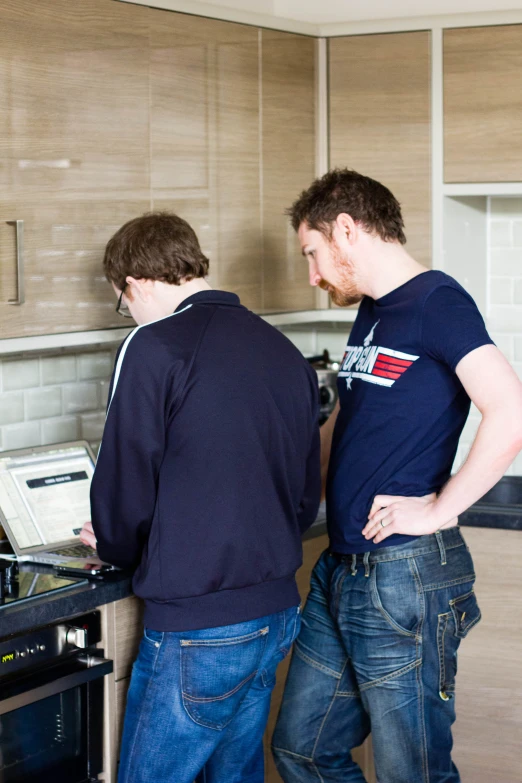 two men stand in the middle of the kitchen working