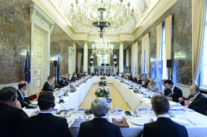 a group of people sit at tables for a long meeting