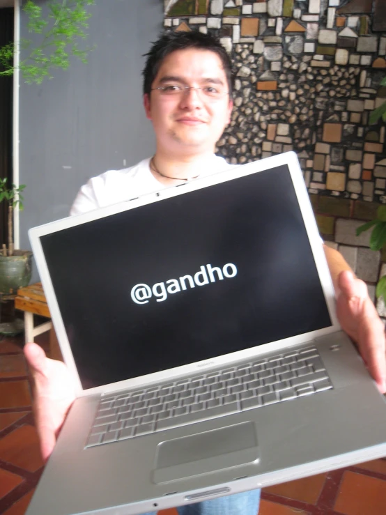 man holding up laptop with screen displaying word that says @ gandinho