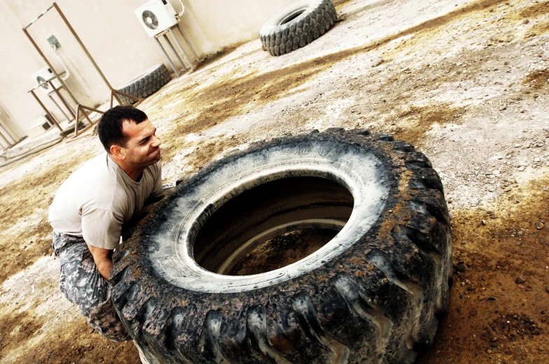 a man sitting on top of a tire in a dirt field