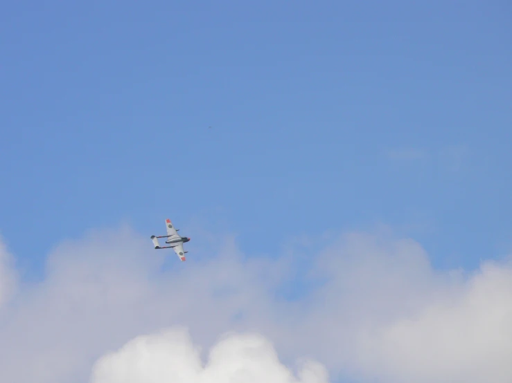 a airplane flying high in the sky on a partly cloudy day