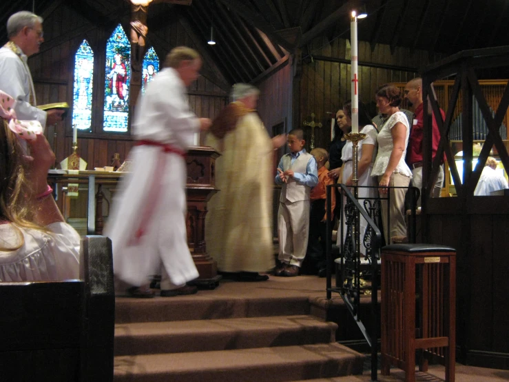 people are standing around while the priest is holding a cross