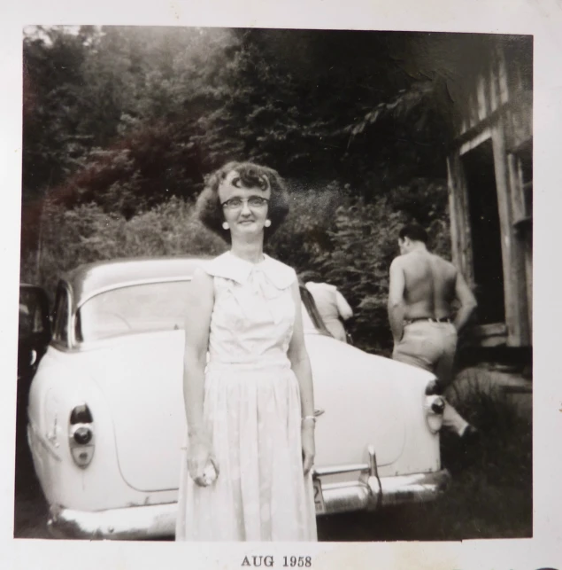 a woman is standing by her car near men