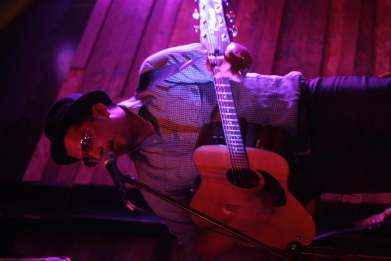 man with sunglasses playing a guitar on stage