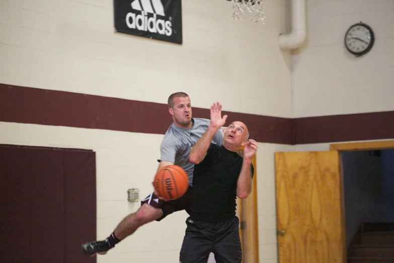 two men playing basketball in a gym with a mirror