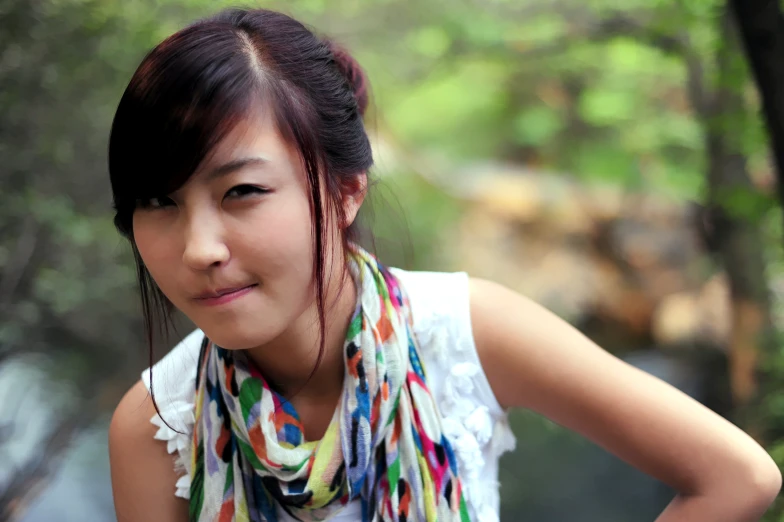 a young asian woman stands next to a forest