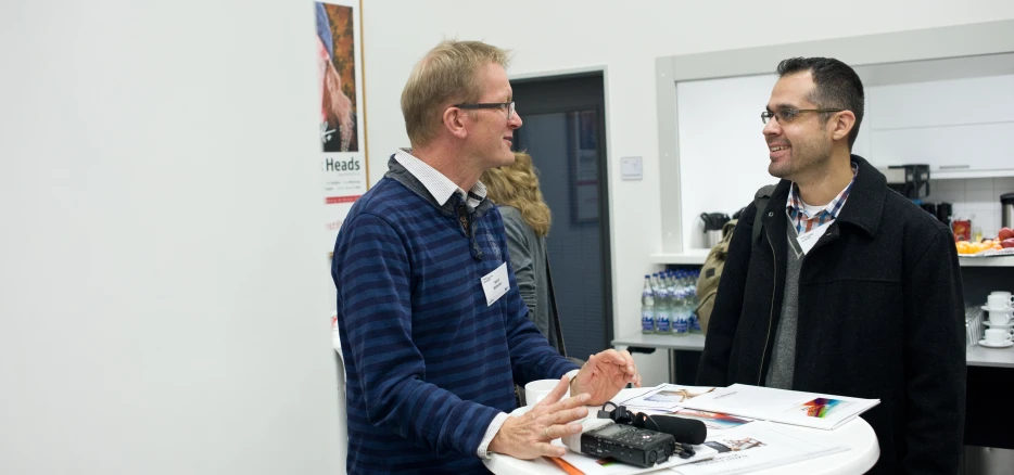 two men are in a white room holding soing