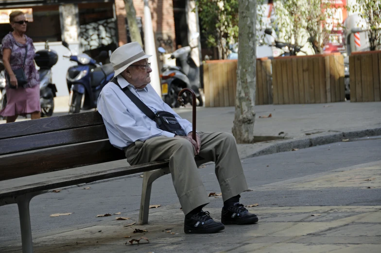 an old man sitting on a park bench holding a cane