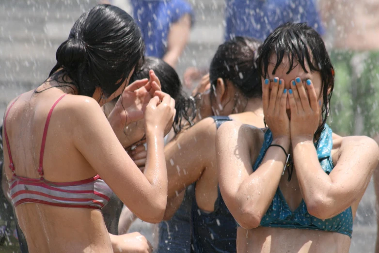 four young women are standing in the fountain