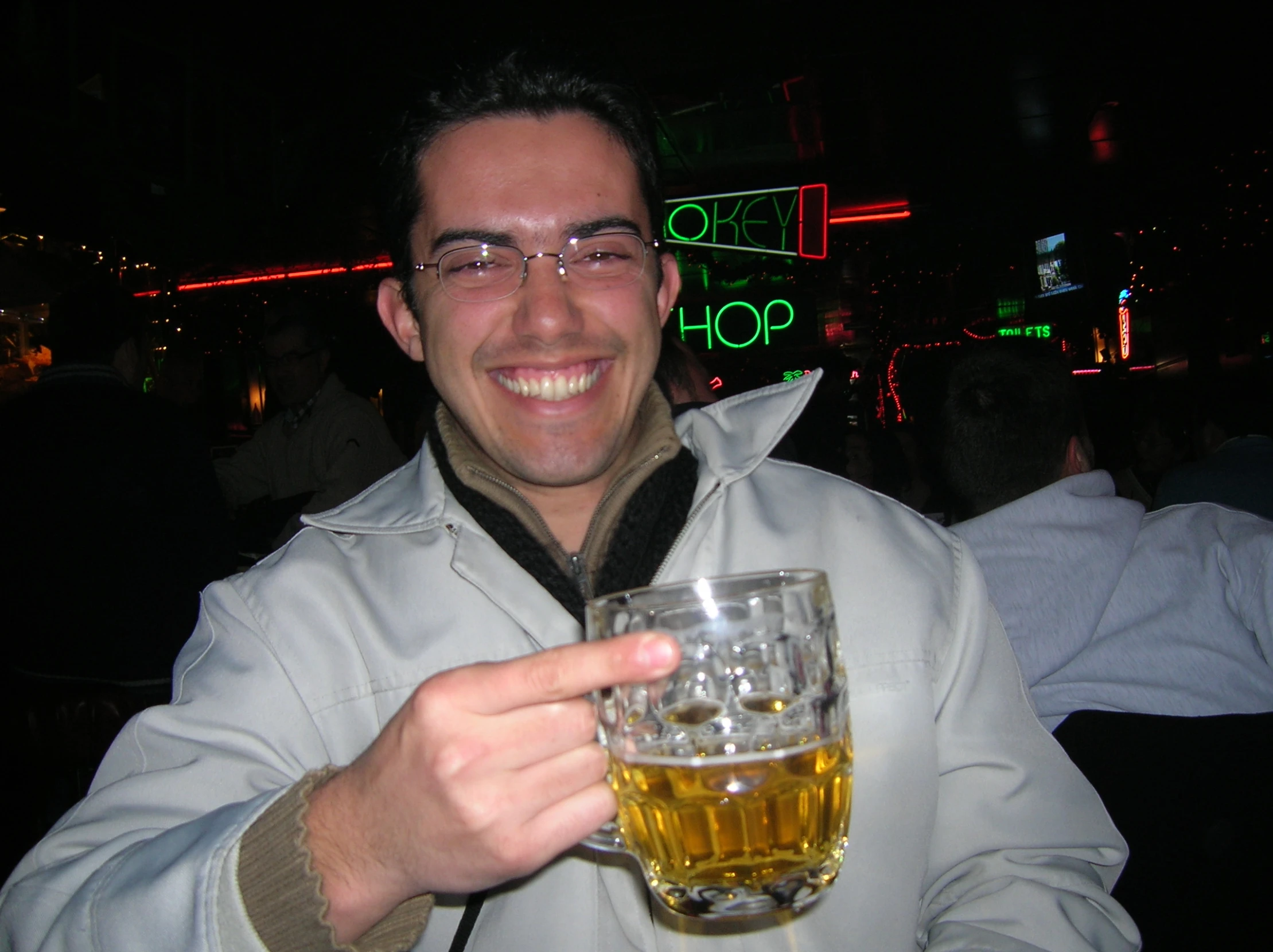 a man with glasses holds up a glass of beer