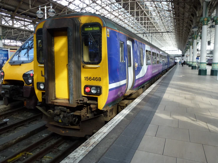 blue and yellow passenger train pulled into a train station