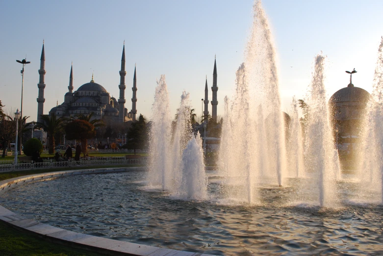 a water fountain in front of several ornate blue domed buildings