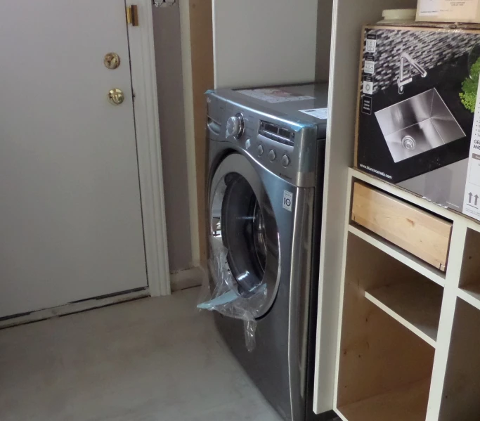 a room with a small dryer in it and another closet behind it