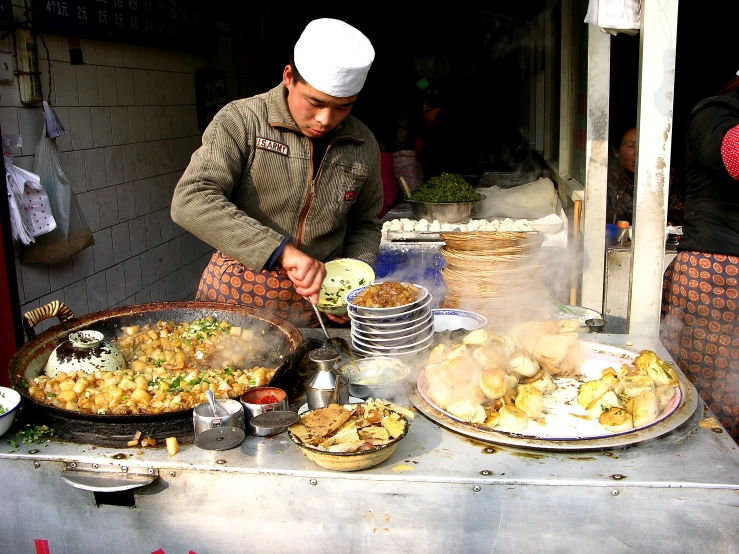 a man cooking at an outdoor food stall