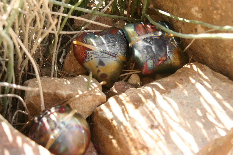 a couple of small glass ornaments laying on top of rocks