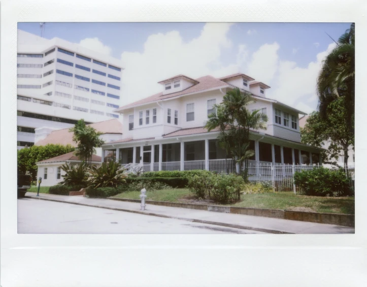 a tall white house on the corner with palm trees in front