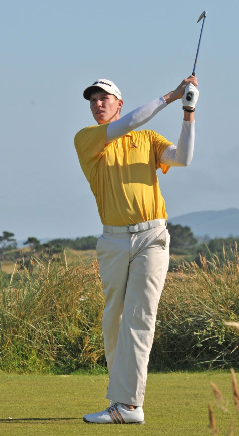 a man on a field swings a golf club