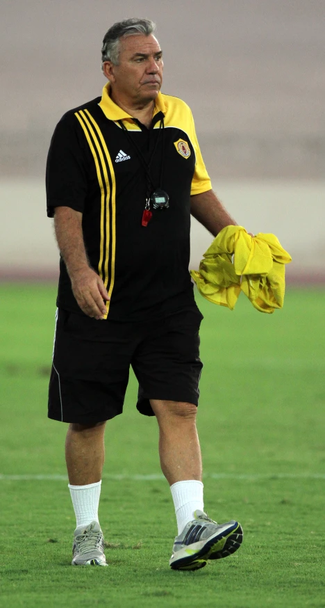 a coach looks on while standing on a soccer field