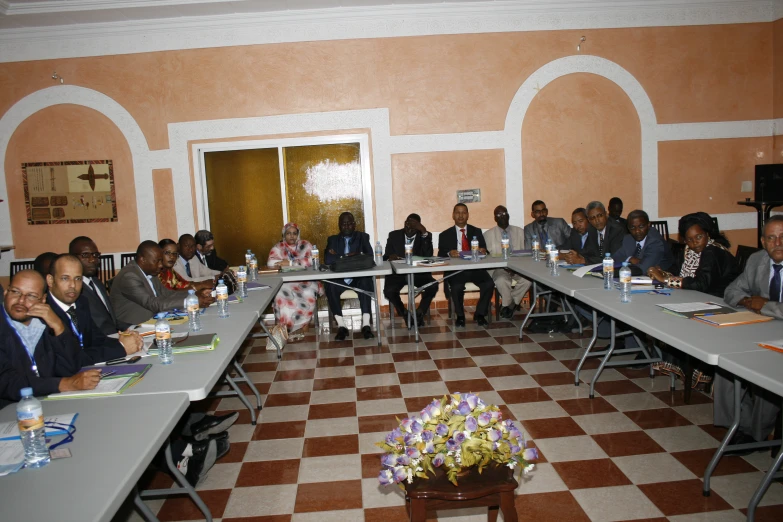 a large group of people are sitting at long table