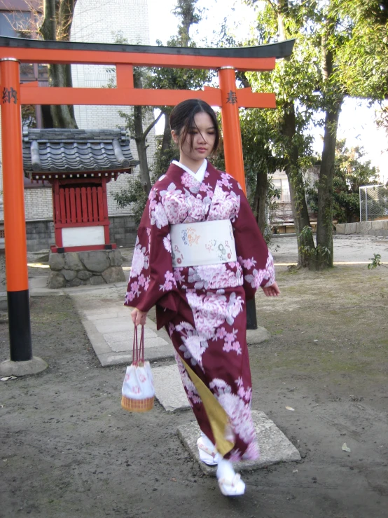 woman in pink kimono walking past a wooden fence