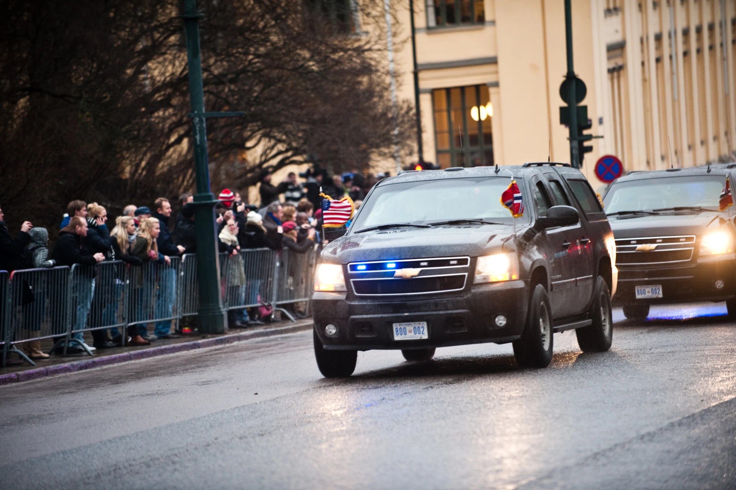 two cars are driving along with a crowd watching