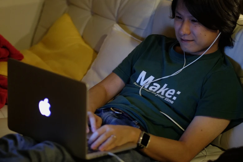 a boy wearing headphones and sitting in front of a laptop