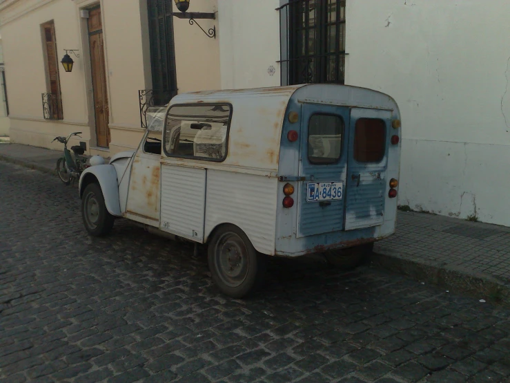 an old blue and white car is parked on the side of the street