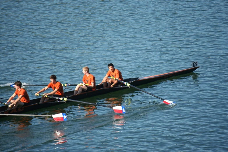 a group of four men rowing down a lake