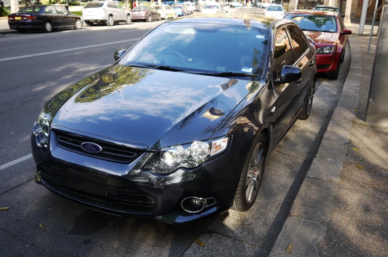 black car parked on street with cars behind it