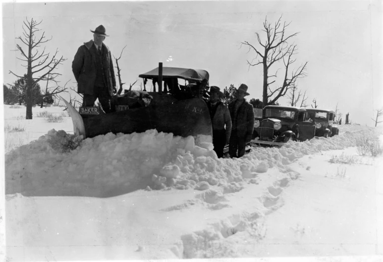 men standing on a snowy road next to old cars