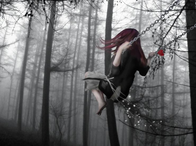 a girl in chains is swinging on a tree