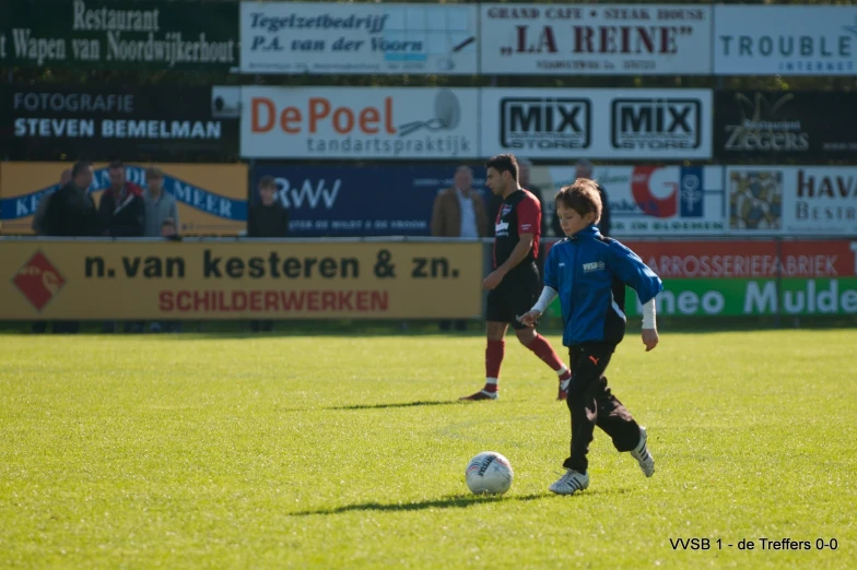 a small boy is kicking around a soccer ball