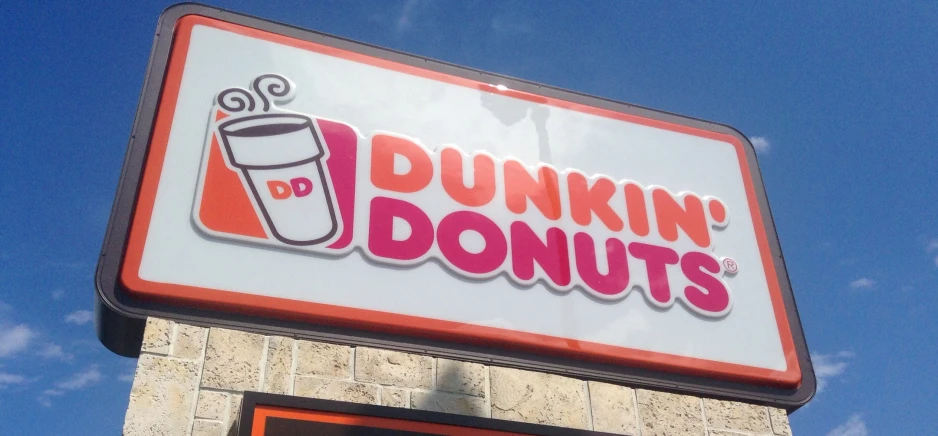 a dunkin'donuts sign hanging off the side of a building