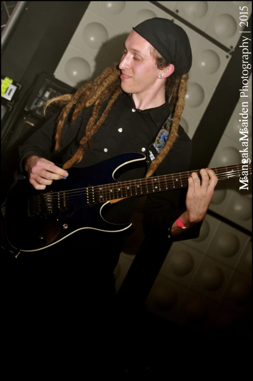 a man with dreadlocks holding a black guitar