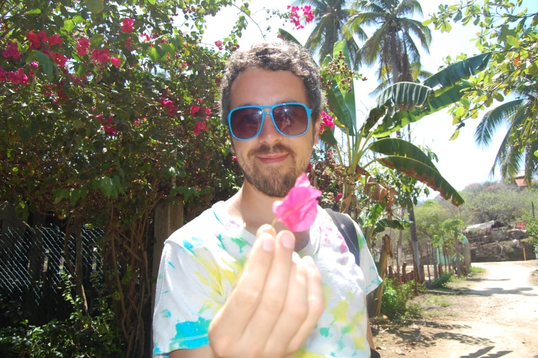 a man wearing sunglasses is holding up a colorful piece of paper