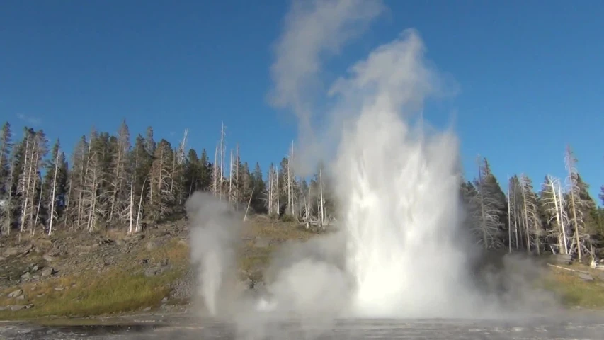 a geyser erupts water from a river in the wilderness