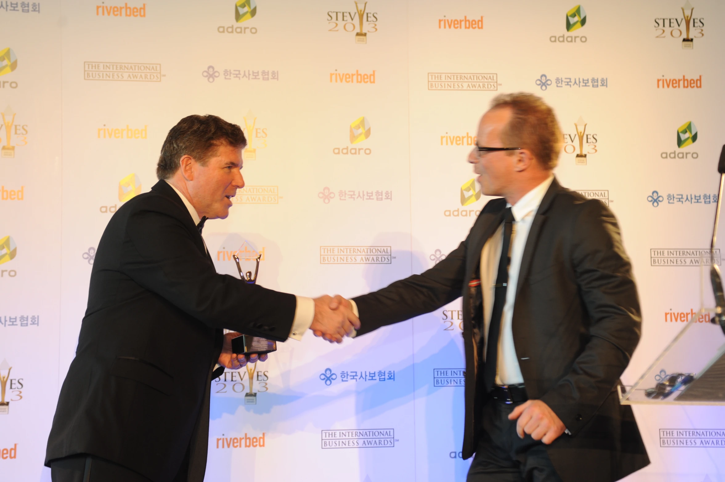 two men shake hands on the red carpet