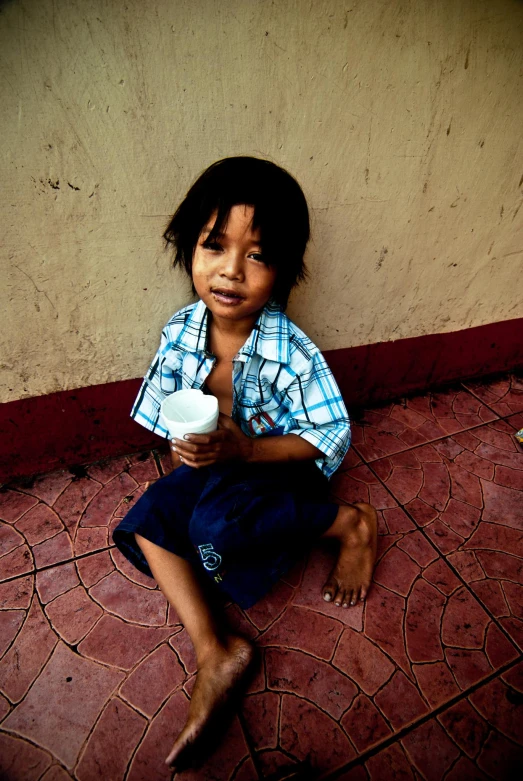 the child sitting on the ground holding a beverage bottle
