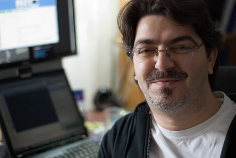 man in glasses sitting in front of an open laptop computer