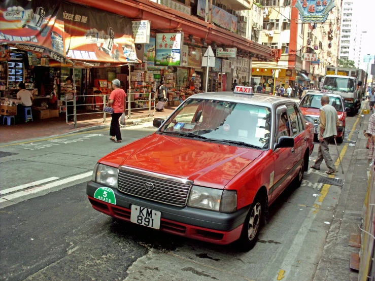 a red car driving down a street next to tall buildings