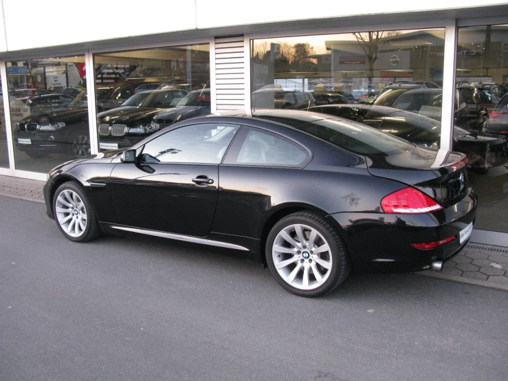 black bmw coupe parked in front of a glass store