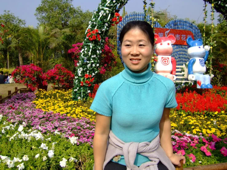 a young woman standing next to flowers and statue