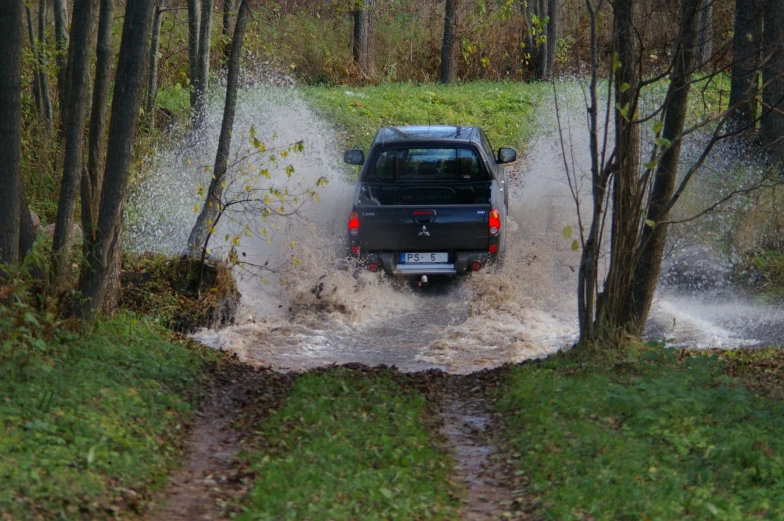 a car driving through water on a wooded road