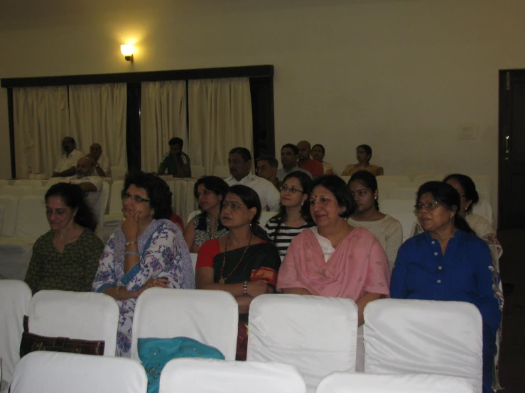 a group of people in a room sitting on white chairs